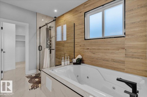 Bathroom featuring a soaking tub with a black faucet, a glass-enclosed shower with a multi-jet panel, and wood-look wall tiling - 207 Starling, Fort Saskatchewan, AB - Indoor Photo Showing Bathroom