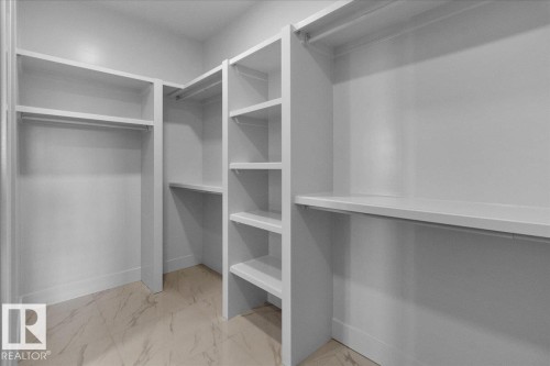 Walk-in closet with built-in shelving, hanging rods, and a light-colored floor - 207 Starling, Fort Saskatchewan, AB - Indoor With Storage