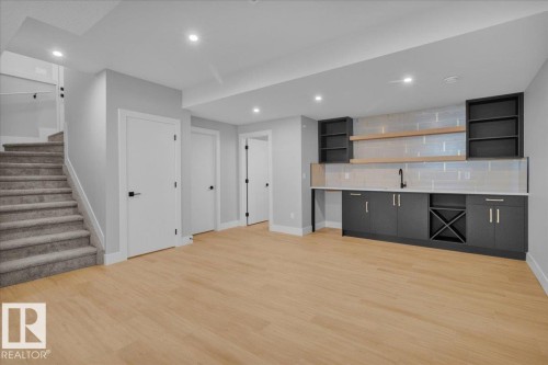 Entertainment area with light wood flooring, a wet bar featuring dark cabinetry, a white countertop, and open shelving - 207 Starling, Fort Saskatchewan, AB - Indoor Photo Showing Other Room