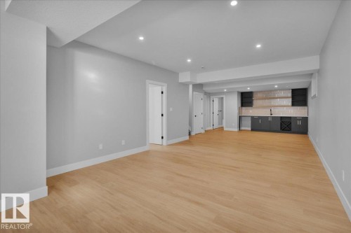 Spacious room featuring light-colored flooring, recessed lighting, and a modern wet bar with dark cabinetry and open shelving - 207 Starling, Fort Saskatchewan, AB - Indoor Photo Showing Other Room