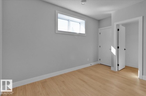 The room features light wood flooring, white baseboards, and a window with white trim - 207 Starling, Fort Saskatchewan, AB - Indoor Photo Showing Other Room