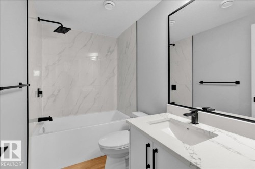 Bathroom featuring a shower and bathtub combination with black fixtures, a white vanity with a rectangular sink, and a large mirror - 207 Starling, Fort Saskatchewan, AB - Indoor Photo Showing Bathroom
