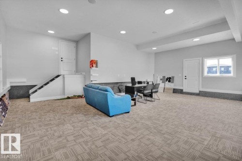 Spacious interior room with light grey walls, recessed lighting, and patterned carpet flooring - 207 Starling, Fort Saskatchewan, AB - Indoor Photo Showing Other Room