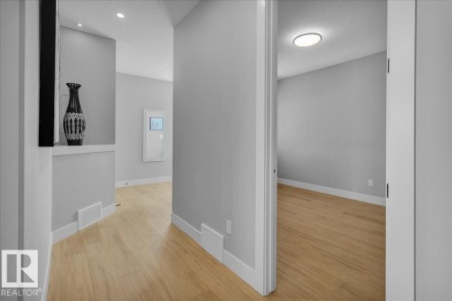 Well-lit interior hallway featuring hardwood floors, light grey walls, and white baseboards - 207 Starling, Fort Saskatchewan, AB - Indoor Photo Showing Other Room