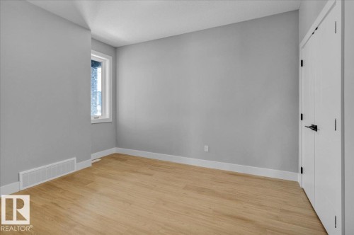 This room features light-colored flooring, a window, and a door with dark hardware - 207 Starling, Fort Saskatchewan, AB - Indoor Photo Showing Other Room