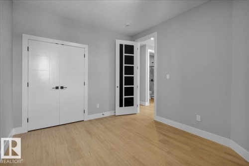 The property features light-colored wood flooring, light grey walls, and white trim - 207 Starling, Fort Saskatchewan, AB - Indoor Photo Showing Other Room