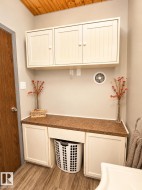 Laundry area featuring built-in cabinetry, wood-finish flooring, a wood plank ceiling, and a countertop with an integrated space for a hamper - 