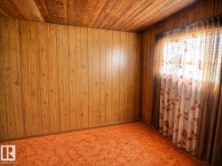 Wood-finish wall paneling and a coordinating planked ceiling characterize this room - 