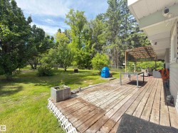 Expansive outdoor deck with a wooden pergola, lattice skirting, and direct access to a large grass yard - 