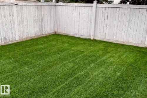 The property features a well-maintained lawn and a light-colored privacy fence - 1007 Goodwin Crest, Edmonton, AB - Outdoor