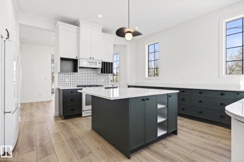 The kitchen features a spacious island with storage, white countertops, and light-toned flooring - 9705 68 Avenue, Edmonton, AB - Indoor Photo Showing Kitchen With Upgraded Kitchen