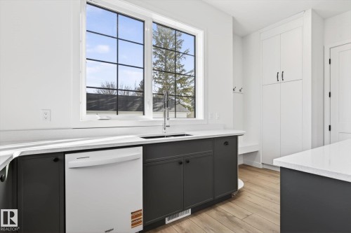 The property features a bright kitchen area with white quartz countertops, a stainless steel sink with a gooseneck faucet, and dark lower cabinetry - 9705 68 Avenue, Edmonton, AB - Indoor Photo Showing Other Room