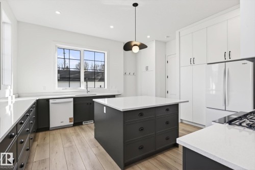 The kitchen features a large window with gridded panes, white countertops, and both white and dark cabinetry - 9705 68 Avenue, Edmonton, AB - Indoor Photo Showing Kitchen