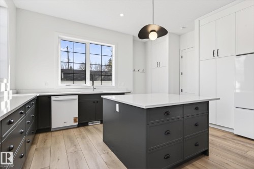 The kitchen features a central island with drawers, dark lower cabinetry, and light upper cabinetry - 9705 68 Avenue, Edmonton, AB - Indoor Photo Showing Kitchen