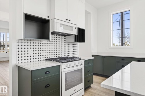 The kitchen features white upper cabinetry, dark green lower cabinetry, and a white oven with a gas cooktop - 9705 68 Avenue, Edmonton, AB - Indoor Photo Showing Other Room