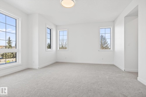 This room features light gray carpeting, pristine white walls, and bright windows with white trim - 9705 68 Avenue, Edmonton, AB - Indoor Photo Showing Other Room