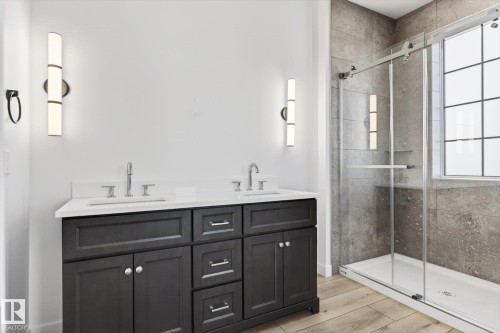 Modern bathroom featuring a double vanity with dark cabinetry, white countertops, and contemporary sconce lighting - 9705 68 Avenue, Edmonton, AB - Indoor Photo Showing Bathroom