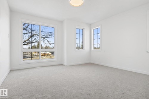 This room features light-colored carpet, white walls, and a contemporary ceiling light fixture - 9705 68 Avenue, Edmonton, AB - Indoor Photo Showing Other Room