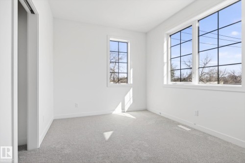 This room features light gray carpeting, pristine white walls, and two windows with multiple panes - 9705 68 Avenue, Edmonton, AB - Indoor Photo Showing Other Room