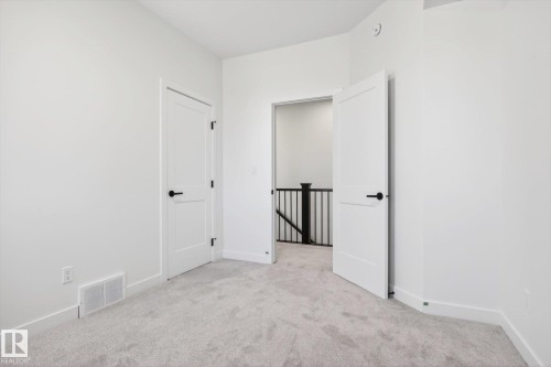 Room featuring light grey carpet, white walls, and white doors with dark hardware - 9705 68 Avenue, Edmonton, AB - Indoor Photo Showing Other Room