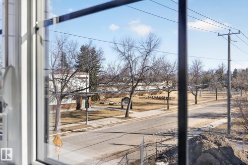 View of the surrounding area from a window, featuring a street, sidewalks, and open green spaces with trees - 9705 68 Avenue, Edmonton, AB - Outdoor With View