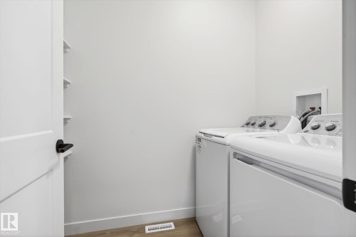 Dedicated laundry area featuring a white top-loading washing machine and a white front-loading dryer, with light-colored flooring - 9705 68 Avenue, Edmonton, AB - Indoor Photo Showing Laundry Room