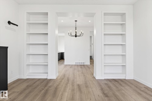 The property features built-in shelving, light-toned wood flooring, and white walls - 9705 68 Avenue, Edmonton, AB - Indoor Photo Showing Other Room