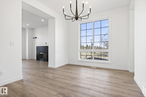 Bright interior space featuring light wood-style flooring, white walls, and a large window with white framing - 9705 68 Avenue, Edmonton, AB - Indoor With Fireplace