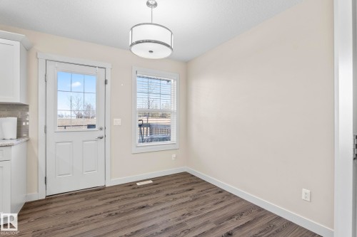 This bright space features durable wood-look flooring, light-colored walls, and a modern ceiling light fixture - 24 4205 30 Street, Edmonton, AB - Indoor Photo Showing Other Room