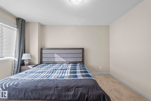 This bedroom features light-colored walls and carpeting, a window with blinds and dark curtains, and a ceiling light fixture - 24 4205 30 Street, Edmonton, AB - Indoor Photo Showing Bedroom