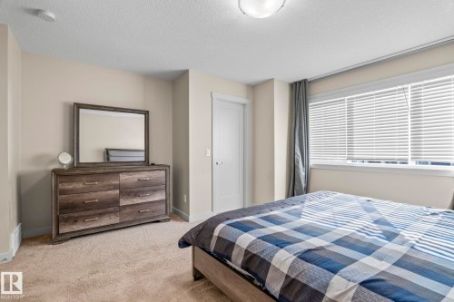 This inviting room features carpeted flooring, a window with blinds providing natural light, and a ceiling light fixture - 24 4205 30 Street, Edmonton, AB - Indoor Photo Showing Bedroom