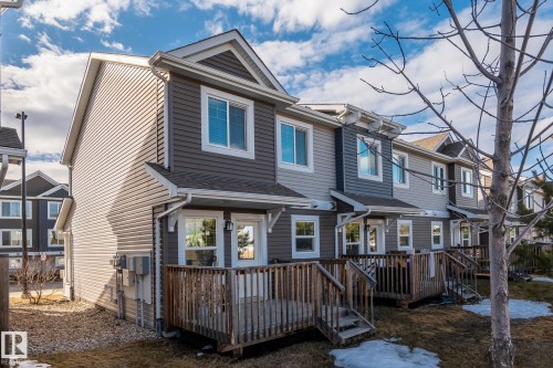 The property features a multi-level structure with a gabled roof and white-framed windows, complemented by a wooden deck and a gravel side yard - 24 4205 30 Street, Edmonton, AB - Outdoor With Deck Patio Veranda
