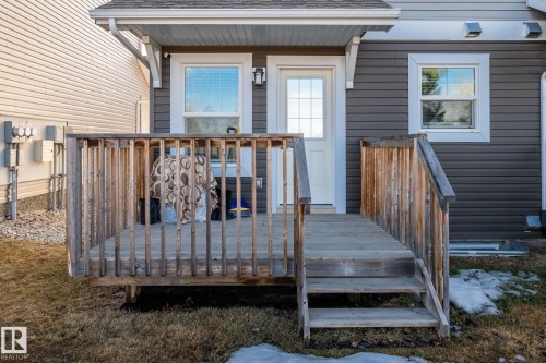 The property features a wooden deck with railing, leading to an exterior door and window, all set against gray horizontal siding - 24 4205 30 Street, Edmonton, AB - Outdoor With Deck Patio Veranda