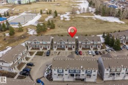 Aerial view of the property and its surrounding area, featuring paved parking areas, green spaces, and an outdoor court - 