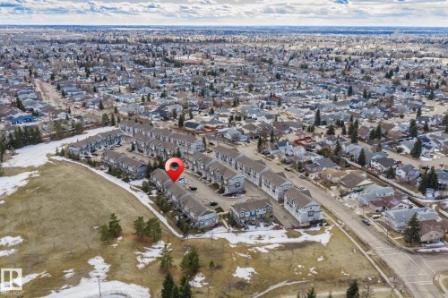 Aerial view of the property and surrounding neighborhood, featuring a row of residential buildings and a nearby street - 24 4205 30 Street, Edmonton, AB - Outdoor With View