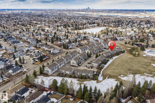 Aerial view of the community, showcasing surrounding residential properties, green spaces, and a distant cityscape - 24 4205 30 Street, Edmonton, AB - Outdoor With View