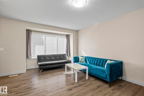 The property features durable flooring throughout, a large window with blinds, and light-colored walls - 24 4205 30 Street, Edmonton, AB - Indoor Photo Showing Living Room