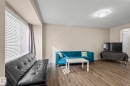 Living area featuring light wood-style flooring, a large window with blinds, and neutral-toned walls - 24 4205 30 Street, Edmonton, AB  - Indoor 