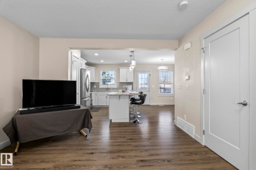 Living area featuring wood-look flooring and light-colored walls, with an open view into the kitchen - 24 4205 30 Street, Edmonton, AB - Indoor Photo Showing Living Room