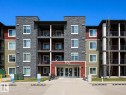 The property features a building with a stone facade, balconies, and an entryway with a visible building number - 209 107, Watt Commom, Edmonton, AB 