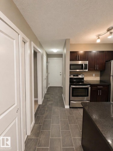 The property includes a kitchen with dark cabinetry, stainless steel appliances, and a dark countertop - 209 107, Watt Commom, Edmonton, AB 