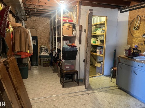 The property includes a basement space with exposed wooden ceiling beams and a stone wall section - 55131 Range Road 83, Rural Yellowhead, AB - Indoor Photo Showing Basement