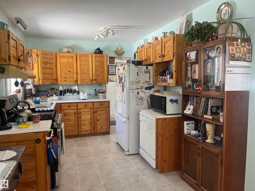 The kitchen features extensive wooden cabinetry, a white countertop, and a tiled floor - 55131 Range Road 83, Rural Yellowhead, AB - Indoor Photo Showing Kitchen