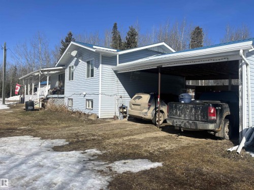 The property features light blue siding, a covered porch, and a covered carport - 55131 Range Road 83, Rural Yellowhead, AB - Outdoor With Exterior