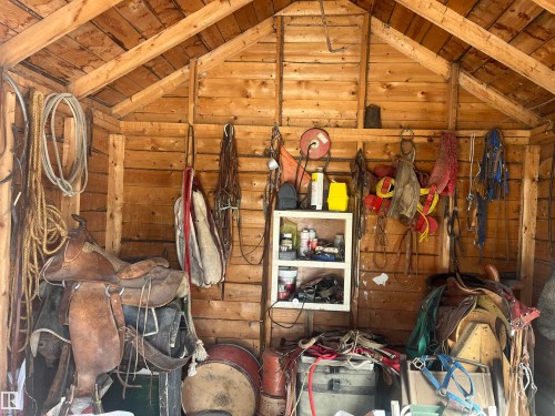 The property includes a shed with unfinished wood walls and ceiling beams, providing practical storage space - 55131 Range Road 83, Rural Yellowhead, AB - Indoor