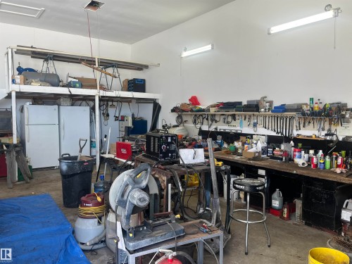 The property features an expansive workshop area with a loft storage space, two refrigerators, and a built-in workbench with tool storage - 55131 Range Road 83, Rural Yellowhead, AB - Indoor Photo Showing Other Room