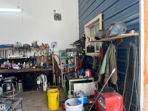 The property features a workshop area with white walls and a blue corrugated wall, equipped with a workbench and shelving - 55131 Range Road 83, Rural Yellowhead, AB - Indoor