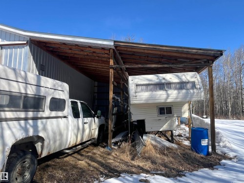 This property features a sturdy metal-sided building with a wooden lean-to structure, offering additional covered space - 55131 Range Road 83, Rural Yellowhead, AB - Outdoor With Exterior