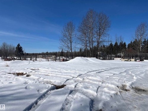 The property features a large open area with snow cover, surrounded by mature trees and a wooden fence line - 55131 Range Road 83, Rural Yellowhead, AB - Outdoor With View