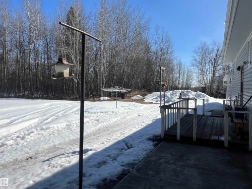 The property features a spacious yard with a snow-covered ground and a wooded backdrop - 55131 Range Road 83, Rural Yellowhead, AB - Outdoor